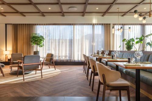 哥本哈根哥本哈根斯堪的纳维亚丽笙酒店的餐厅设有长桌子和椅子以及大窗户。