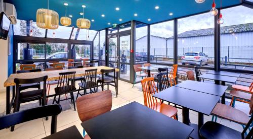 纳博讷Kyriad Direct Narbonne Sud的餐厅设有桌椅和窗户。