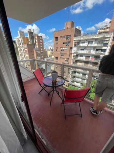 科尔多瓦Chacabuco 36的站在带桌椅的阳台上的人