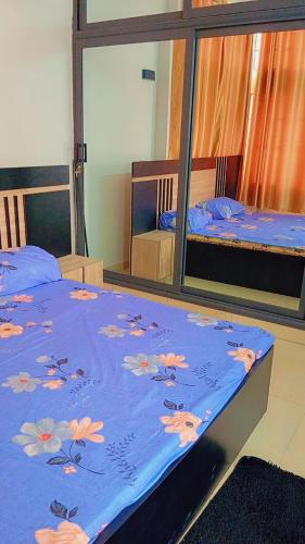 科托努Timba chiclieu的一间卧室配有两张床,带鲜花的蓝色毯子
