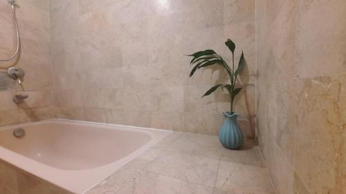 登巴萨Villia magnolia sanur bali 巴厘島玉蘭別墅的浴室设有白色浴缸和花瓶里的植物
