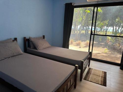 布桑加Magalong Villa at Holy Land in Busuanga的带大窗户的客房内的两张床