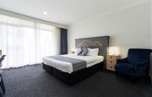 卢拉Leura Gardens Resort的酒店客房,配有一张床和一张蓝色椅子