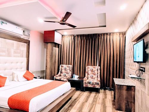 达兰萨拉Hotel King Castle Central Heated & Air cooled的一间卧室配有一张床、两把椅子和电视