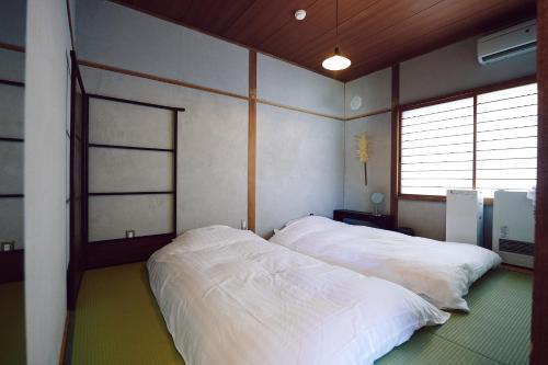 函馆SMALL TOWN HOTEL Hakodate的卧室配有2张白色的床