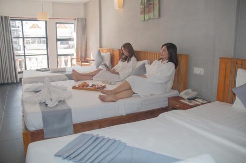 金边格兰德埃里文新大酒店的两名妇女坐在酒店房间的床边