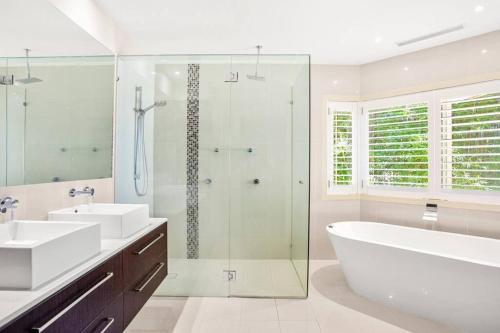黄金海岸Mermaid Waters House的浴室配有2个盥洗盆、浴缸和淋浴。