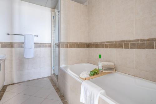 迪拜Frank Porter - Al Badia 2的白色的浴室设有浴缸和淋浴。