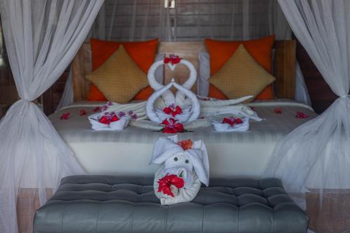 蓝梦岛Tatak Bunut Private Villa的一间卧室,床上有红色的鲜花