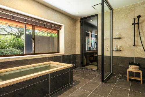 笛吹市Beautiful Japanese Garden Kagetsu的带浴缸和玻璃淋浴间的浴室。