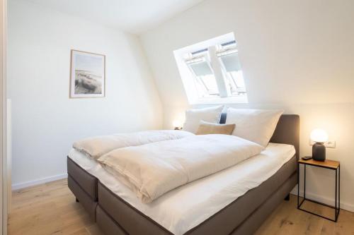 蒂门多弗施特兰德Villa Dornkamp 6 - Luxuriöse Ferienwohnung für 2 Personen inklusive Balkon und Sauna的卧室配有一张大白色床和窗户