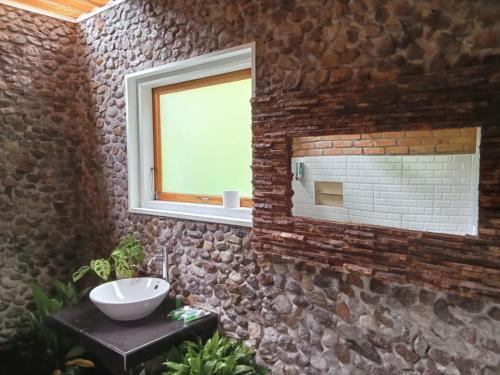 巴东Air Manis Hillside Villa Cafe & Resto的石质浴室设有水槽和镜子