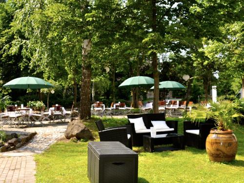 格尔利茨Dein Gutshof Hotel & Ferienwohnungen的一个带桌椅和遮阳伞的花园
