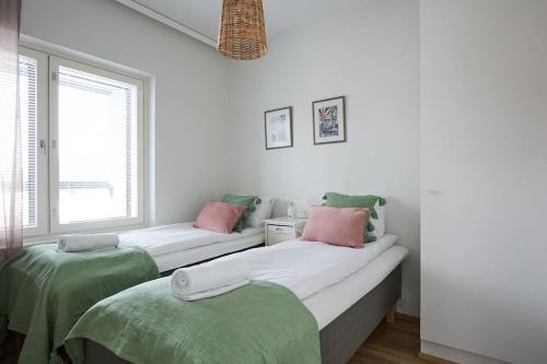 图尔库Saunallinen uudiskohde Logomon vieressä, ilmainen autohallipaikka + Wi-Fi的一间卧室配有两张带绿色和粉红色枕头的床