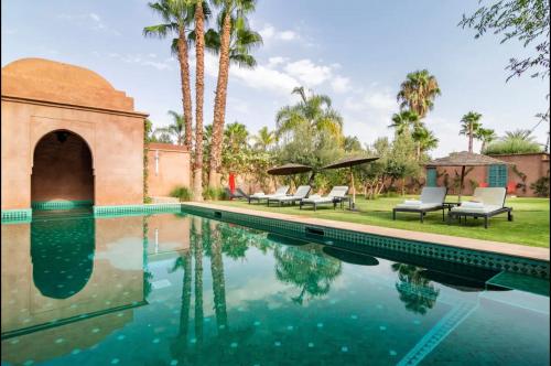 马拉喀什Villa Magtafa的一座房子旁的游泳池,游泳池旁设有椅子和棕榈树