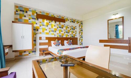 班加罗尔FabHotel Emirates Suites的一间卧室配有一张床和一张玻璃桌