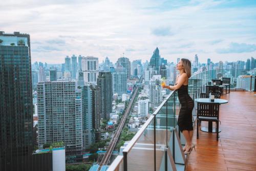曼谷Marriott Executive Apartments Bangkok, Sukhumvit Thonglor的站在阳台边缘的女人喝一杯
