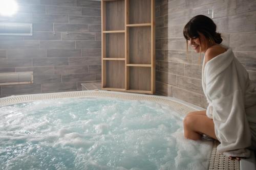 卡斯特乌Hotel & Aparthotel Casteau Resort Mons Soignies的坐在浴室热水浴池中的女人