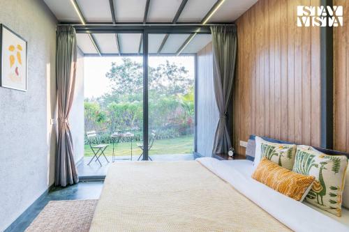 纳西克StayVista's Celeste Villa - Hill-View Retreat with Infinity Pool & Outdoor Jacuzzi的一间卧室设有一张床和一个大窗户