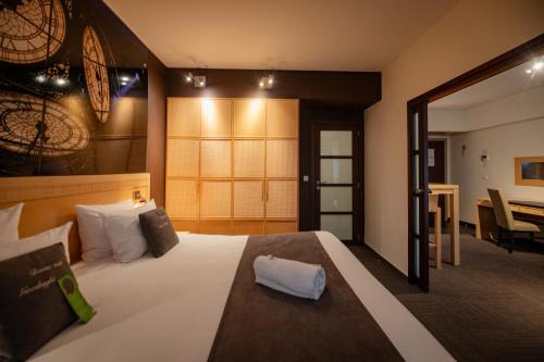 卡斯特乌Hotel & Aparthotel Casteau Resort Mons Soignies的一间带大床的卧室和一间餐厅