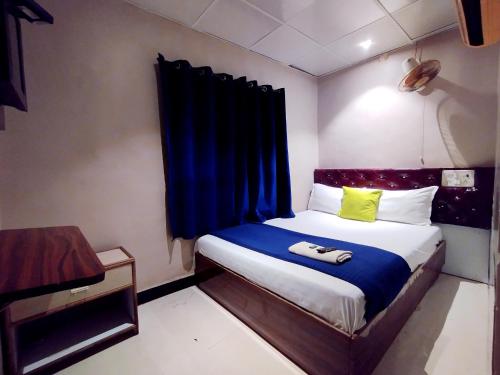孟买Hotel Aspen - Near International Airport的小卧室配有一张带蓝色窗帘的床
