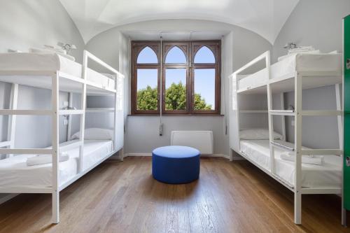 米兰Babila Hostel & Bistrot的一间设有白色双层床和蓝色凳子的房间