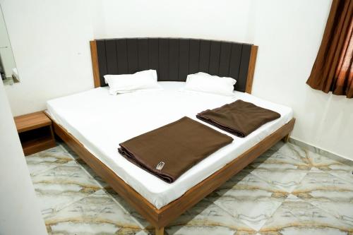 艾哈迈达巴德Hotel Aaram Kalupur的一张铺有白色床单的床和一张棕色的毯子