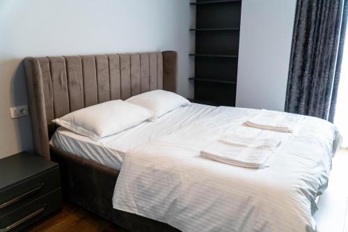 地拉那Signature apartment 5的一张带白色床单的床和两张毛巾