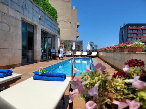 贝鲁特天空套房酒店的站在一座带游泳池的建筑屋顶上的女人