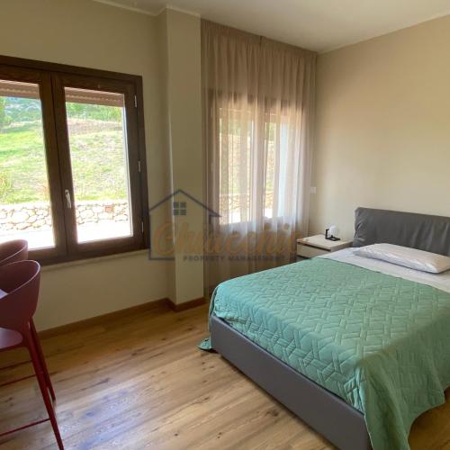 CollepardoVilla La Macchia的一间卧室设有一张床和两个窗户。