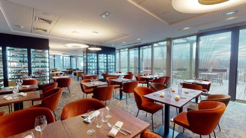 圣普列斯特DoubleTree by Hilton Lyon Eurexpo的餐厅设有桌椅和窗户。