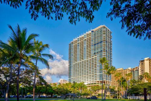 檀香山Ka Laʻi Waikiki Beach, LXR Hotels & Resorts的一座高大的建筑,前面有棕榈树