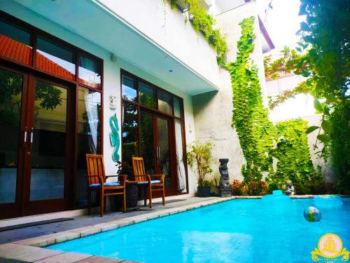 沙努尔3Bedroom Villa Kepiting Sanur的一座带两把椅子的游泳池,位于大楼旁
