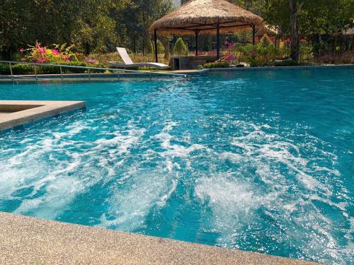 山甘烹Baan Pingkan Wellness Resort的蓝色的海水游泳池,设有凉亭