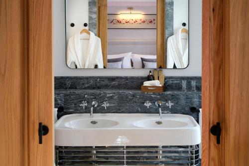萨拉曼卡Eunice Hotel Gastronómico的浴室设有白色水槽和两面镜子