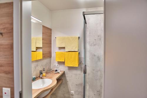 瓦尔德明兴格鲁伯兰德酒店的浴室设有水槽和带黄毛巾的淋浴。
