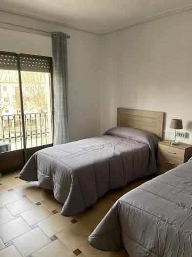 巴埃萨APARTAMENTOS LEONOR的一间卧室设有两张床和大窗户