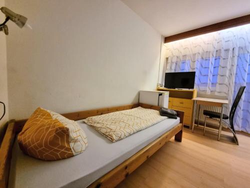 卡尔斯巴德Monteurzimmer - Karlsbad的一间卧室配有一张床、一张书桌和一台电视