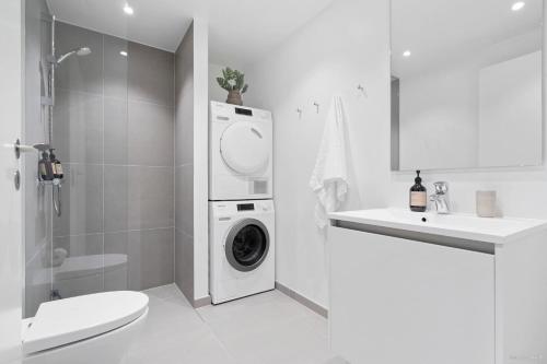 奥胡斯Seaside apartment with magical balcony view的白色的浴室设有洗衣机和烘干机。