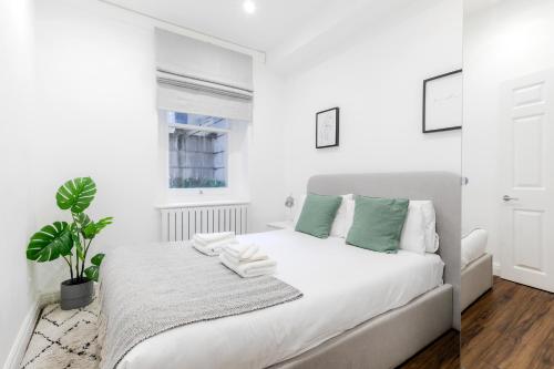 伦敦Luxury Apartments - Fitzrovia的一间白色卧室,配有床和植物