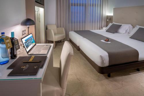 巴塞罗那Hotel SERHS Del Port的酒店客房配有一张床、一张书桌和一台笔记本电脑