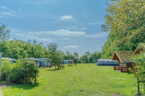 Nieuw-WeerdingeMini Camping Drentse Monden的一个带帐篷、桌子和树木的大院子