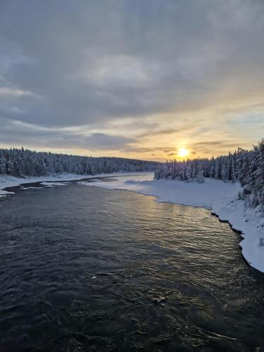 JockÖverkalix Kalixalven Lodge Jockfall的雪中河流,太阳在背后
