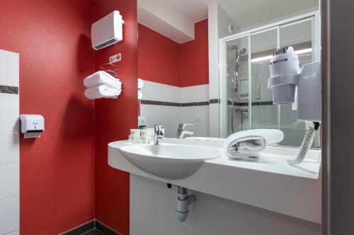 贝利罗曼维利而巴黎马恩河谷Ace酒店的浴室设有白色水槽和红色的墙壁。