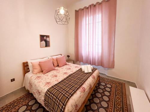 比萨La Casa di Eli的一间卧室配有带粉红色枕头的床和窗户。