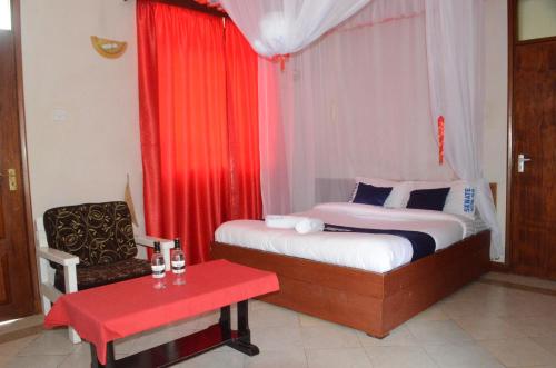 ThikaHOTEL SENATE JUJA的一间卧室配有一张床、一把椅子和红色窗帘