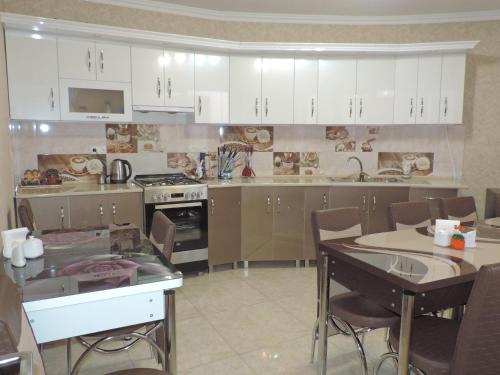 阿哈尔齐赫Hotel Lotus的厨房配有白色橱柜和桌椅