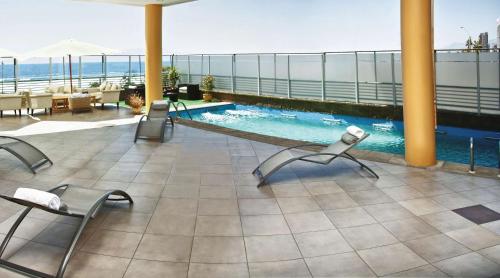 安托法加斯塔安托法加斯塔NH酒店的一座带椅子的庭院和一座位于大楼内的游泳池
