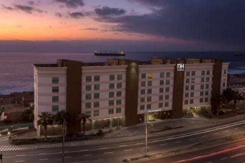 安托法加斯塔安托法加斯塔NH酒店的一座以大海为背景的街道上的建筑