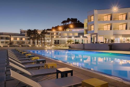 马赛马赛豪酒店的一座大楼前的游泳池,配有躺椅
